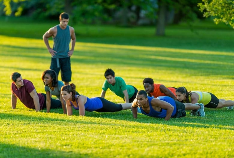 personal trainer e il suo gruppo di clienti svolgono un workout all'aperto