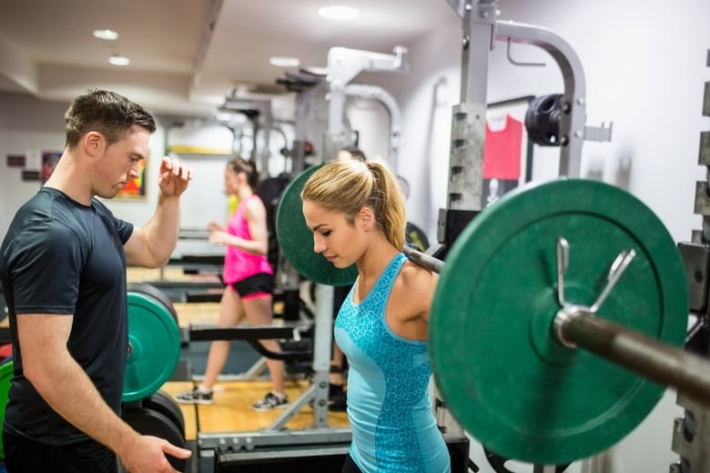 Personal trainer che allena una sua cliente in palestra