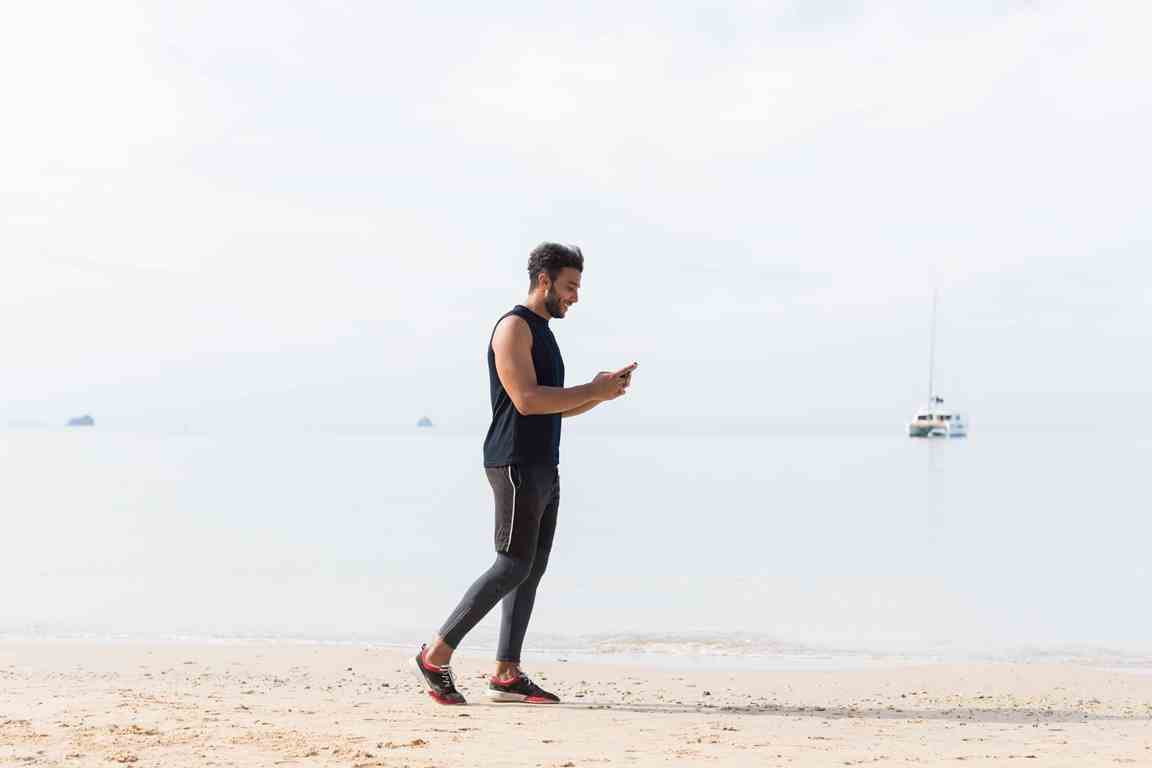 ragazzo si allena in spiaggia con lo smartphone REVOO